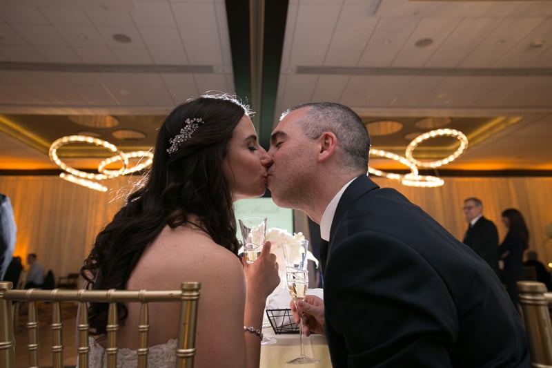 bride and groom kiss at their head table at westin