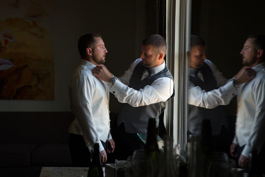 best man helping groom get dressed