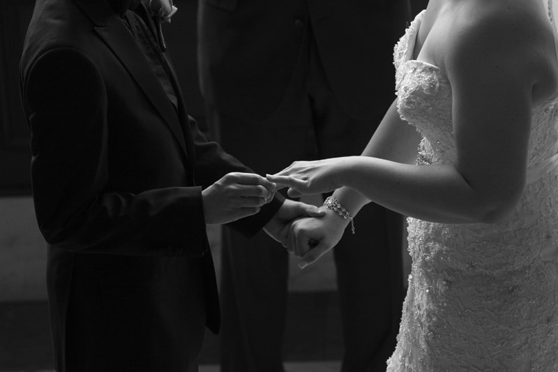 groom putting wedding ring on bride
