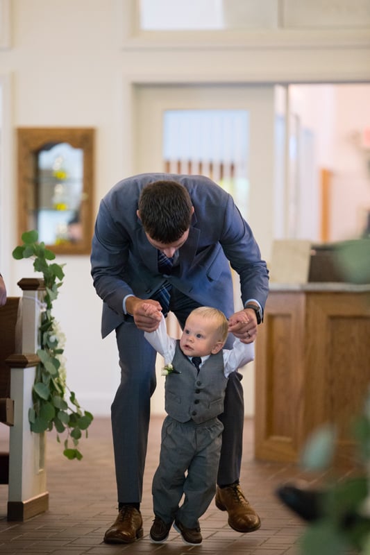 ring bearer being helped down the aisle