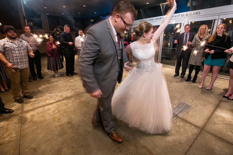 bride and groom exit their wedding reception at akron art museum