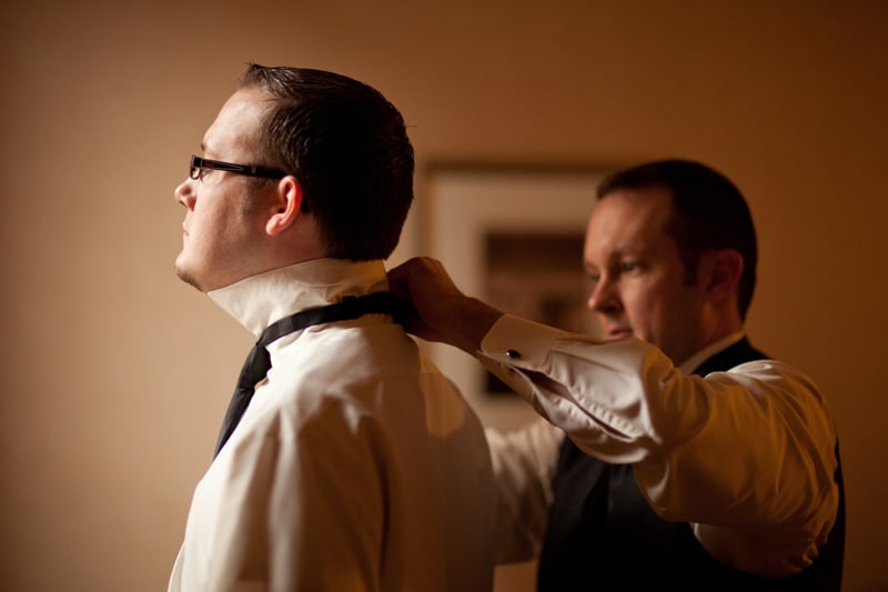 best man helping groom with tie