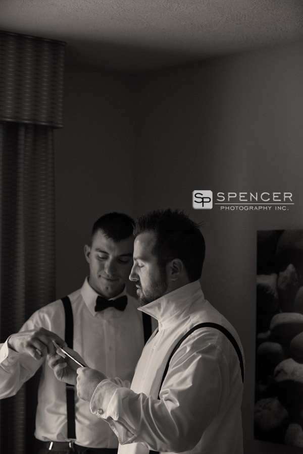 best man helping groom with tie