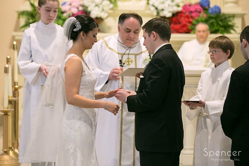 groom putting on wedding ring at weddng ceremony at Holy Rosary