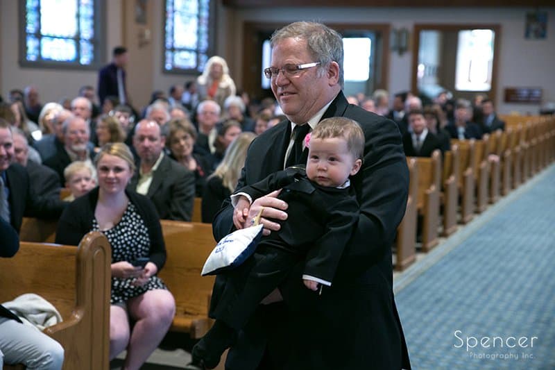 grandpa carrying ring bearer during wedding ceremony