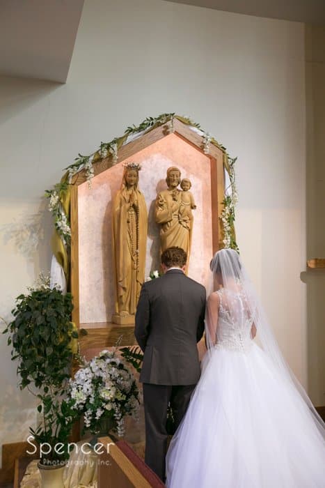 bride and groom standing at Virgin Mary at St. Barnabas