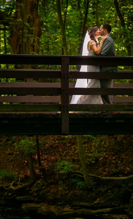  bride and groom kissing on a bridge