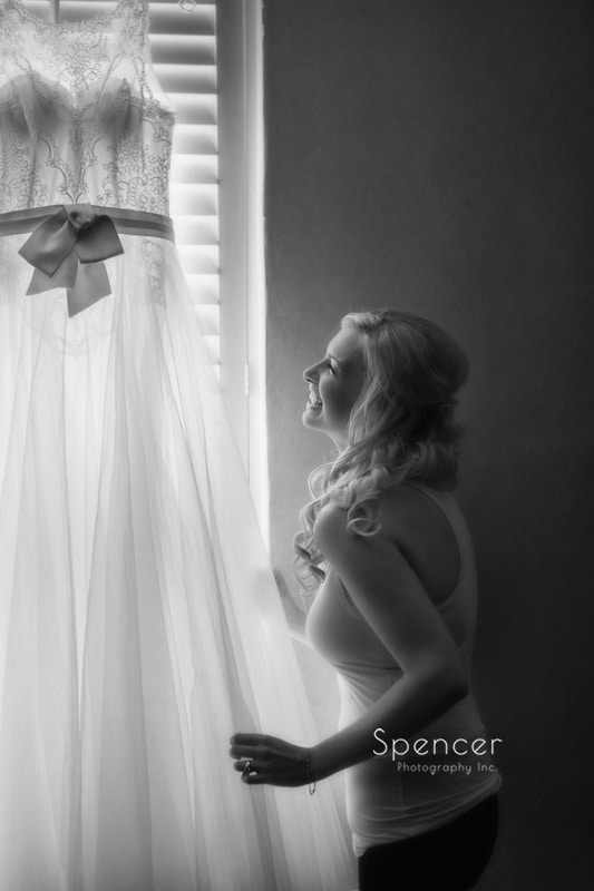 black and white picture of bride adjusting wedding dress