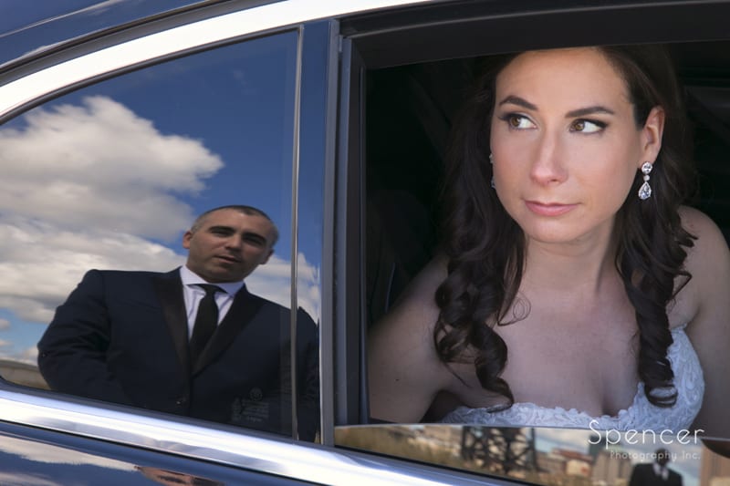 bride looks at groom with his reflection in limo window