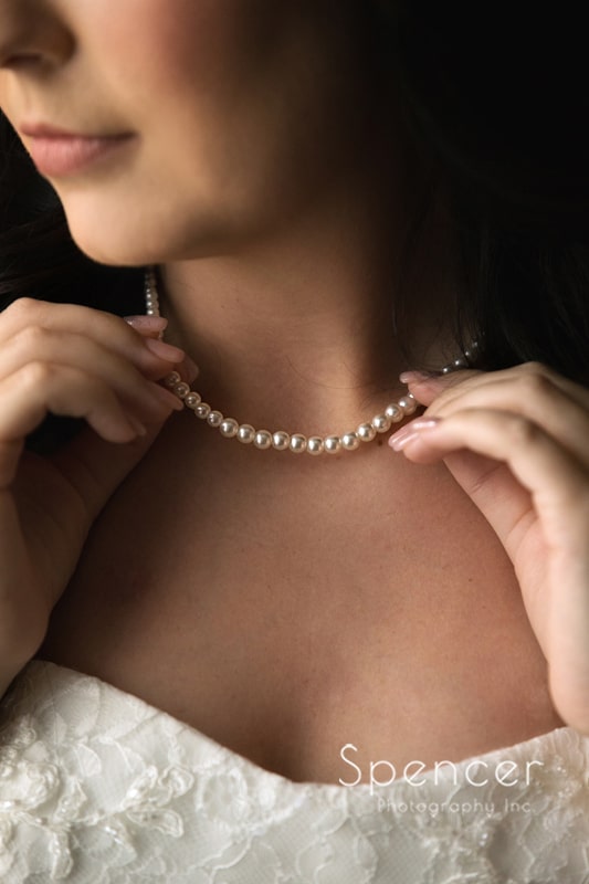 bride holding wedding day pearl necklace