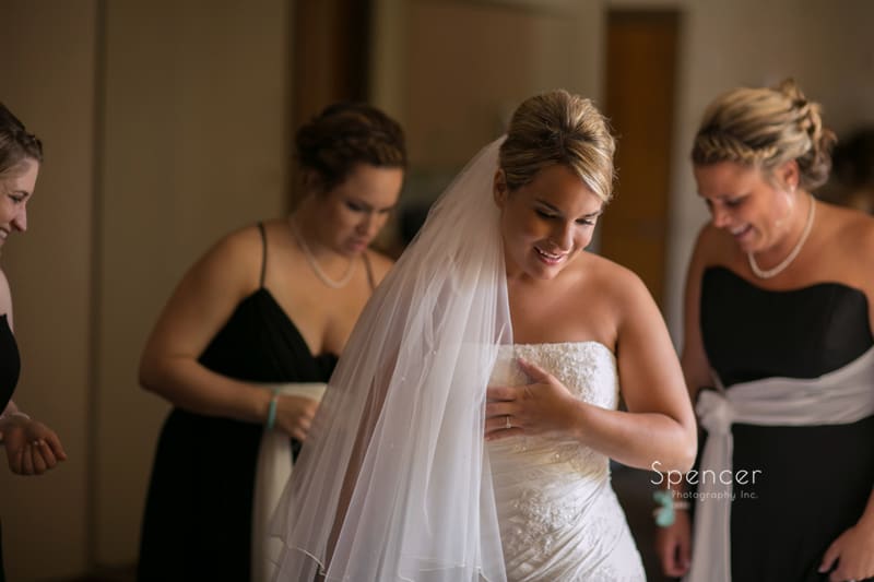 bride smiling while putting on her wedding dress