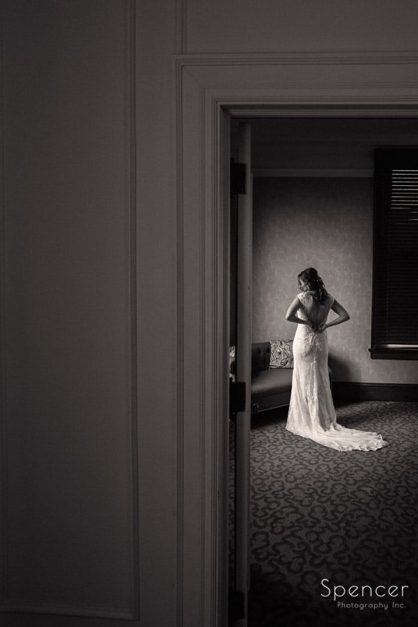 bride zipping dress before wedding at Greystone Hall Akron