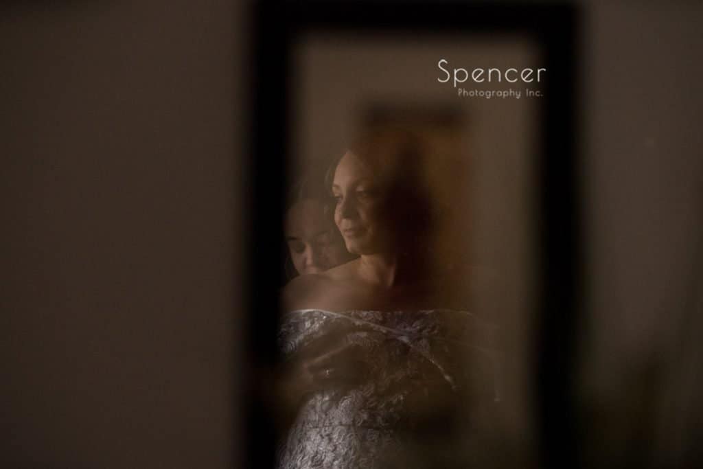reflection of bride putting dress on