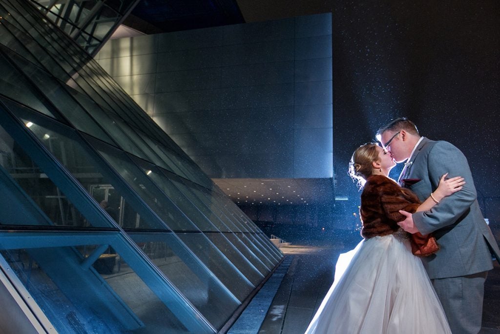 couple kissing in front of Akron Art Museum on wedding day