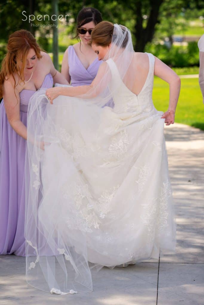 bridesmaid helping bride with wedding dress outside Cleveland Museum of Art