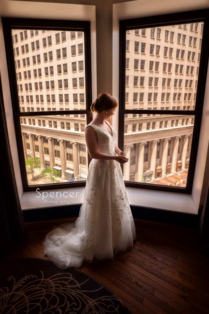 bride standing in her wedding dress at window forWedding Pictures at Kimpton Schofield Hotel