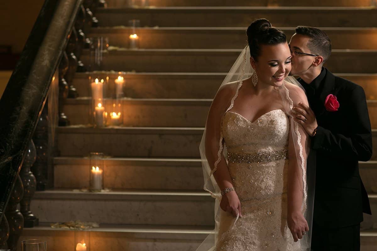 groom kissing bride on cheek on staircase at Cleveland Union Club