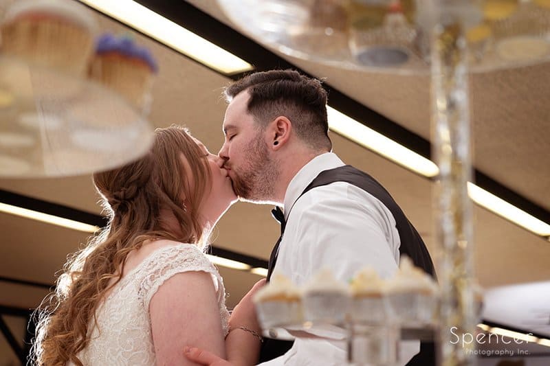 bride and groom kiss after cutting wedding cake