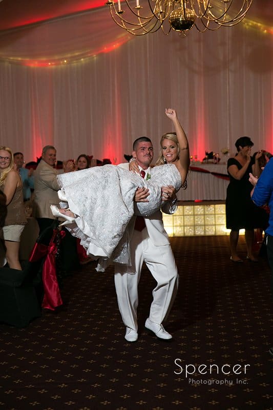  groom carrying bride into their wedding reception at Michaud's Strongsville