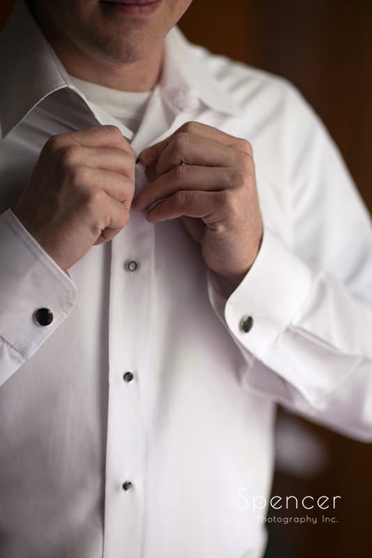 groom buttoning his shirt