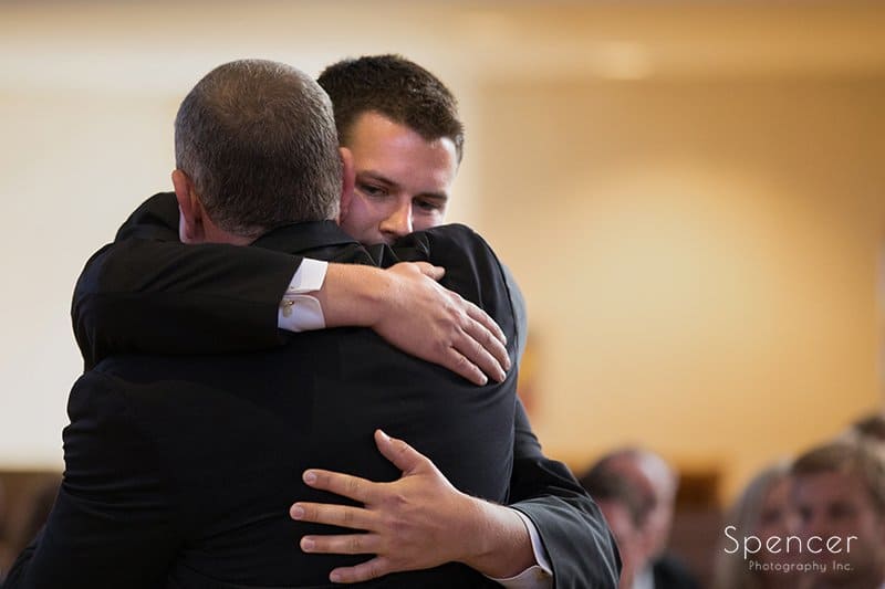 groom hugging dad at wedding ceremony at St. Hilary