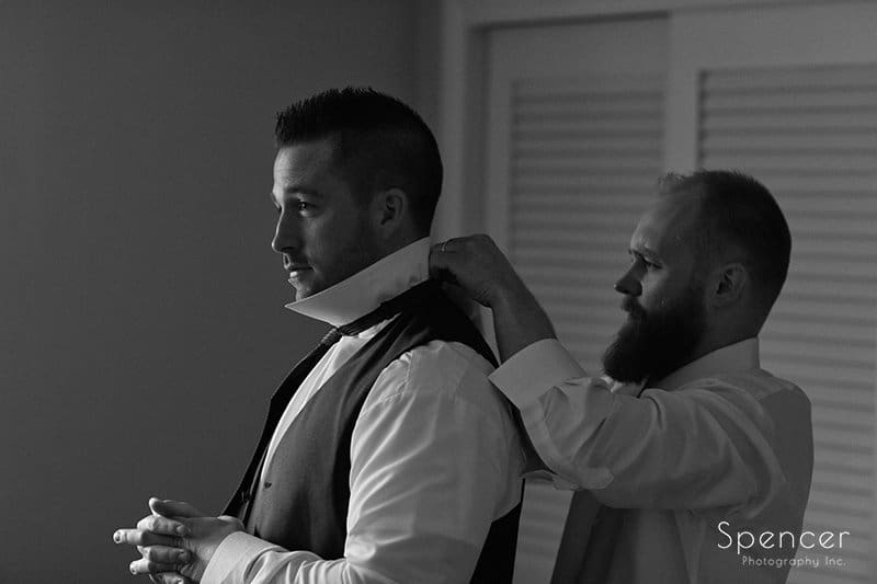 best man helping groom with his tie
