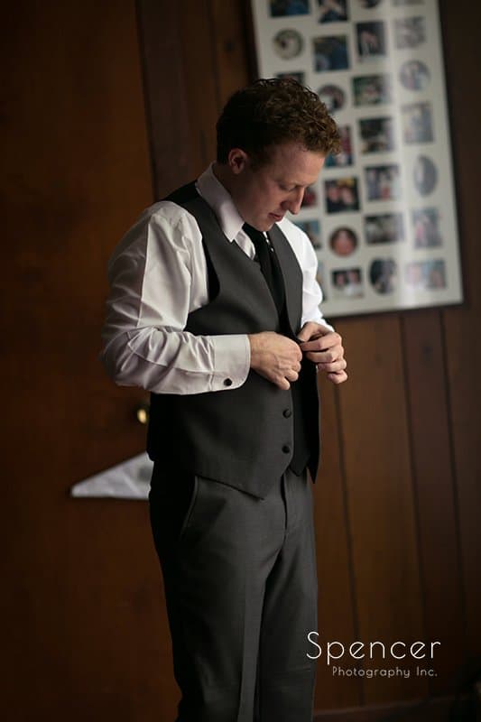 groom buttoning up his wedding tux