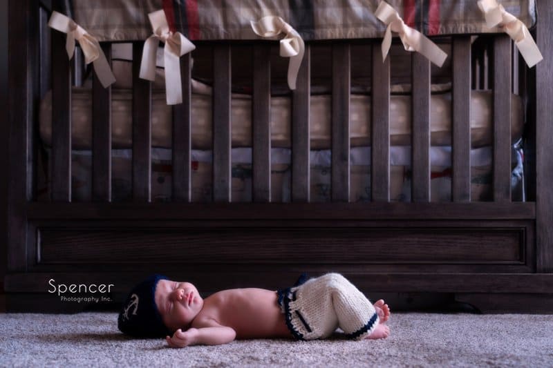 cleveland newborn baby laying in front of crib