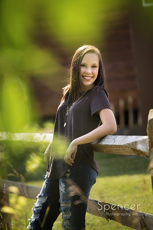 senior high school girl leaning on fence at white birch barn