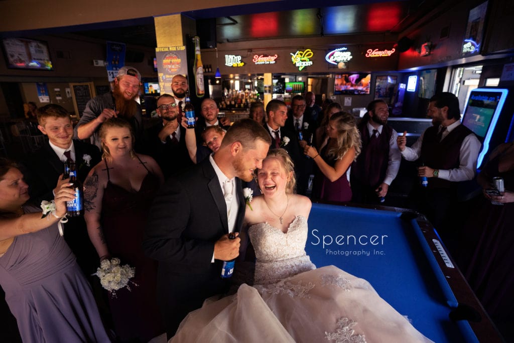  bride and groom laughing on pool table