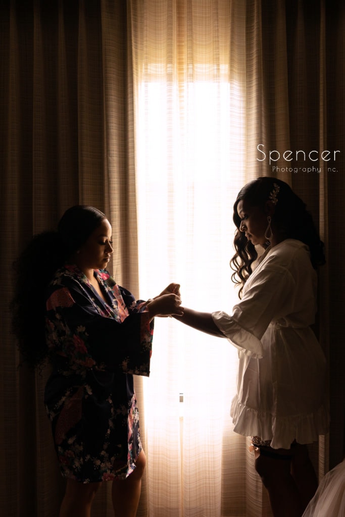 maid of honor helping bride with braclet at Embassy Suites Canton