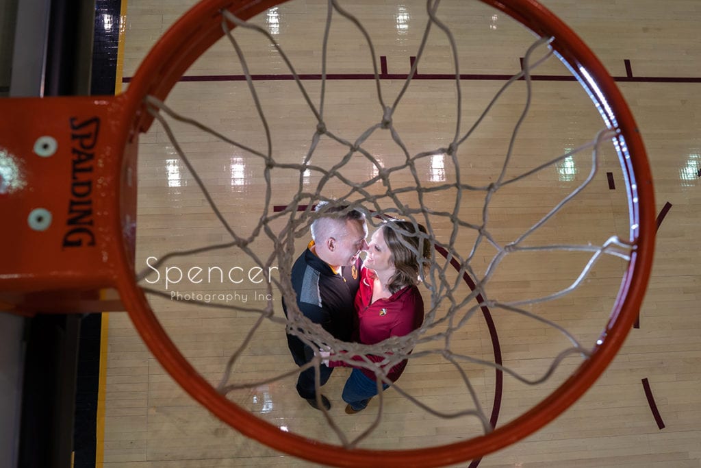 couple under basketball hoop in engagement pictures at Rocket Mortgage Fieldhouse