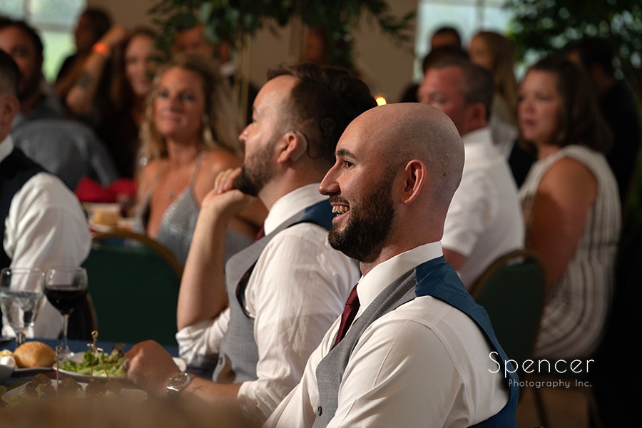 groom laughing during speeches at gay wedding reception at Stan Hywet