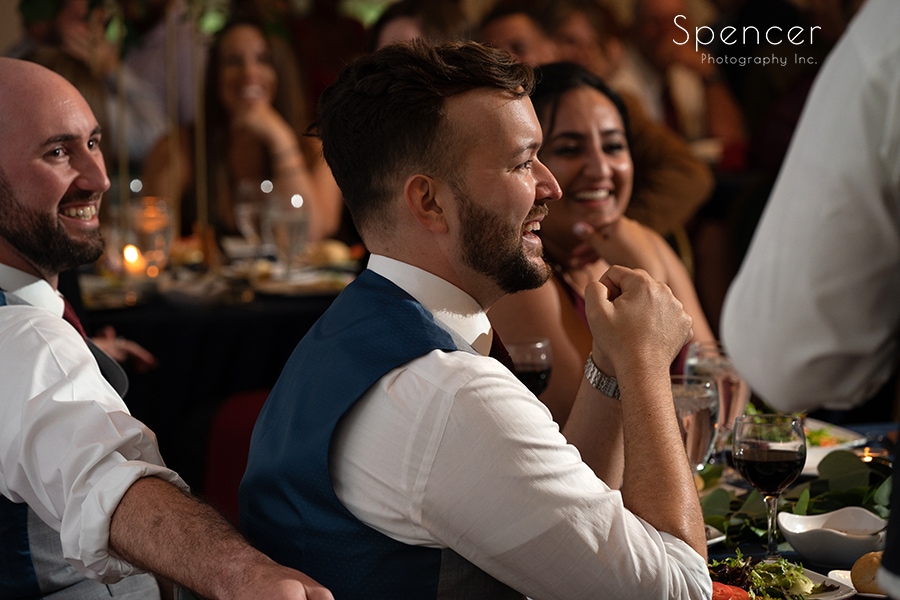 groom laughs during speeches at gay wedding reception