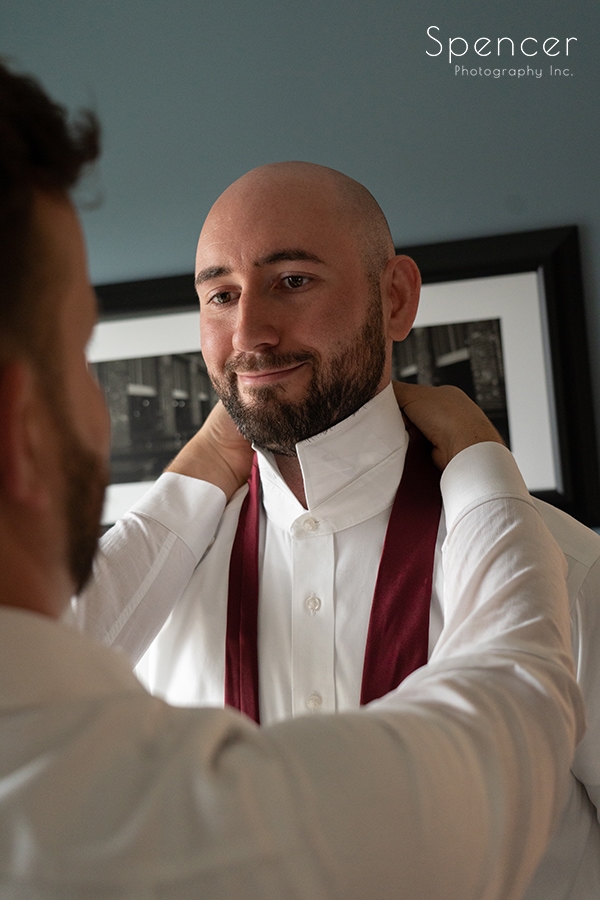 grooms putting tie on before same sex wedding