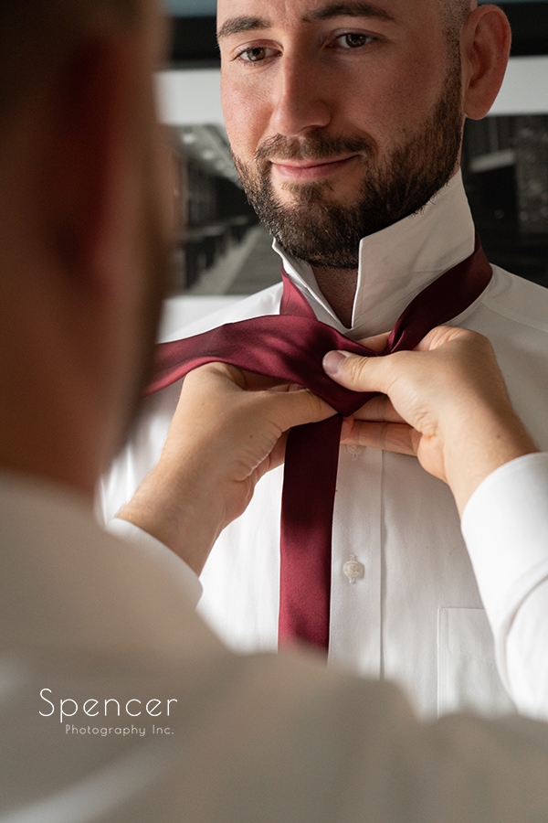 groom look at groom at he ties his tie