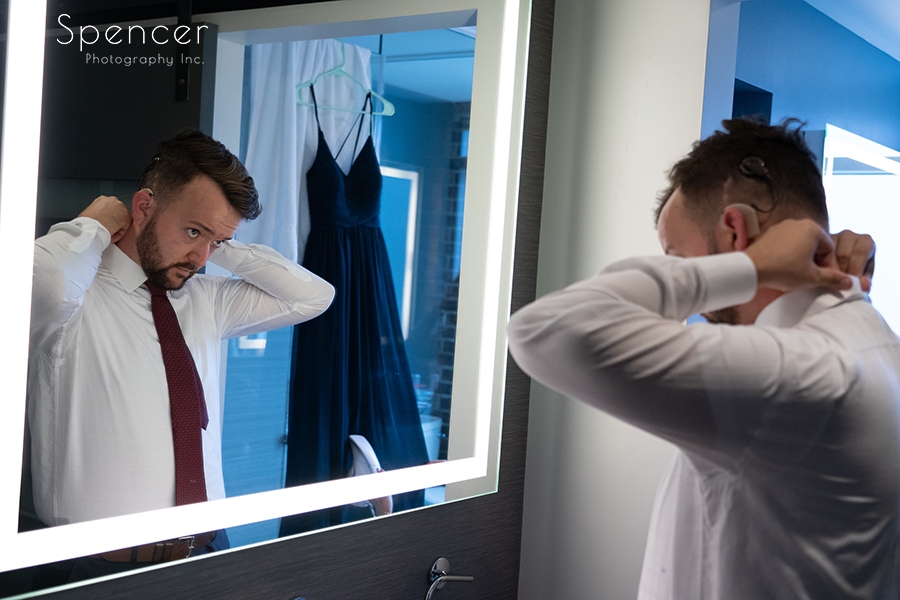 groom fixing tie in mirror at Courtyard by Marriott Akron