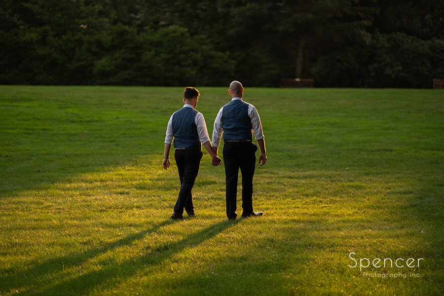 grooms walking towards mansion after same sex wedding at Stan Hywet