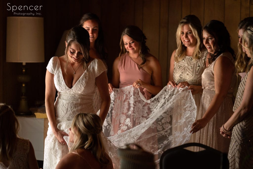 Bridesmaids helping bride into dress at Patterson Fruit Farm