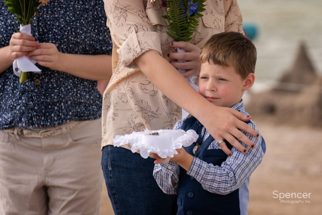 ring bearer holding pillow at wedding at Dock's Beach House