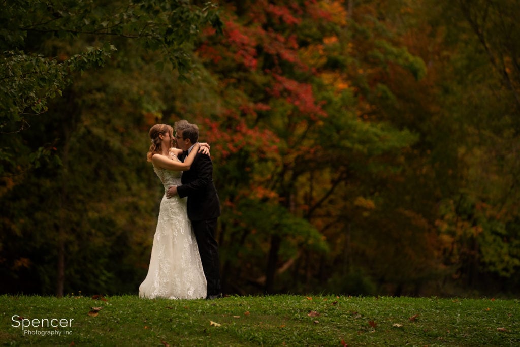 bride and groom kissing in fall wedding photo
