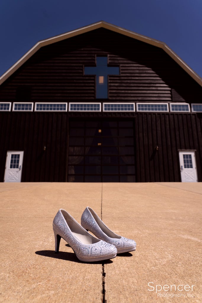 brides wedding shoes behind Parker Barn