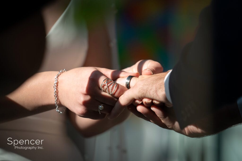 bride putting wedding band on groom at Akron Art Museum