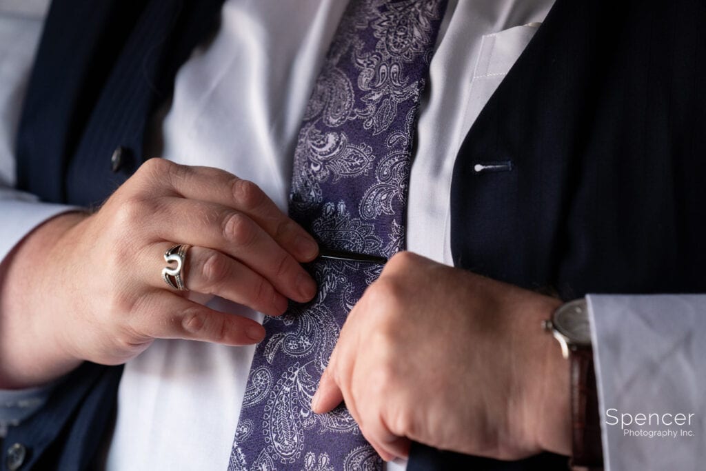 groom adjusting tie clip