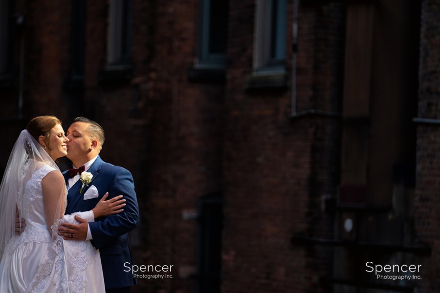 groom kissing bride and downtown Cleveland