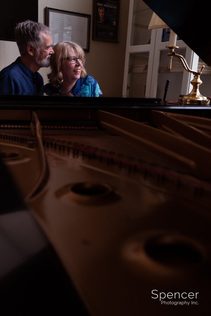 couple smiling at piano at akron engagement pictures