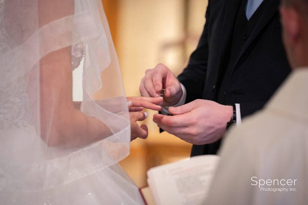 groom putting on brides wedding ring