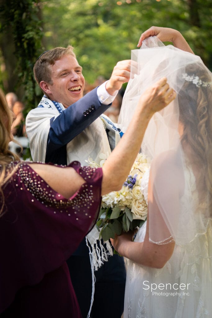 groom helping bride with veil