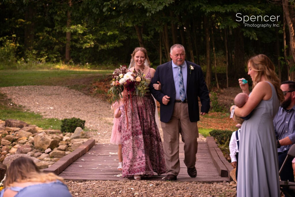 bride and father walking to outdoor wedding ceremony