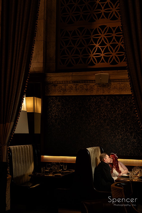 bride and groom kissing in booth at Marble Room Cleveland